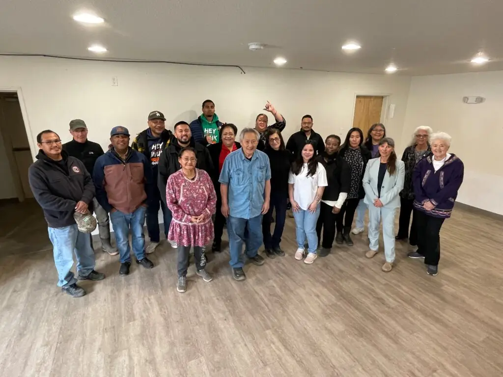 A diverse group of training participants standing as a group in front of a white wall